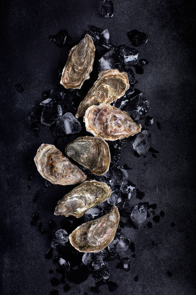 Closed oysters on black background. Healthy sea food - Fotoğraf, Görsel