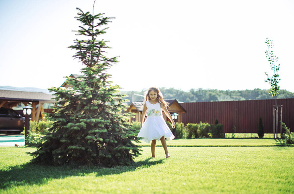 Girl playing at a big yard of wooden house - Foto, afbeelding