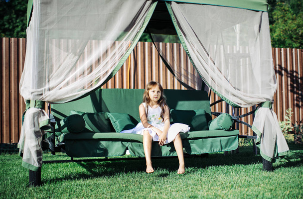 Little girl at the yard on a garden swing  - Valokuva, kuva