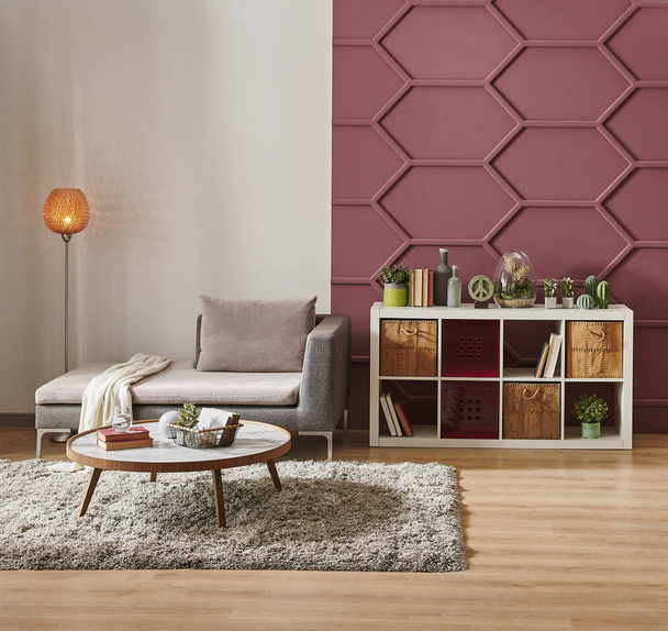 Koristeellinen olohuone valkoinen ja viininpunainen seinä tausta, harmaa sohva ja keskellä taulukon koristelu, sisustus
 - Valokuva, kuva
