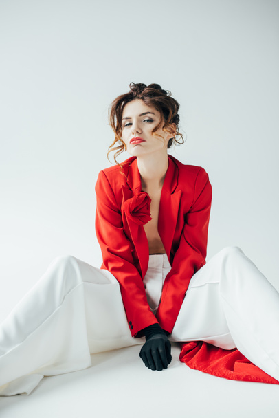 mujer joven disgustada y de moda con el pelo rojo sentado en blanco
  - Foto, Imagen
