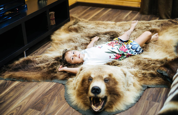 Little girl with a bearskin at home - Fotó, kép
