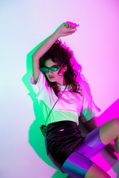 trendy young woman in sunglasses sitting on purple with gradient  - Foto, Imagem