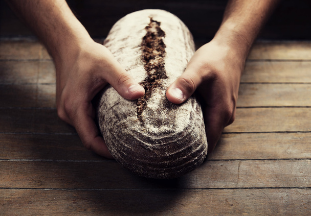 Baker's hands with a bread - Foto, afbeelding