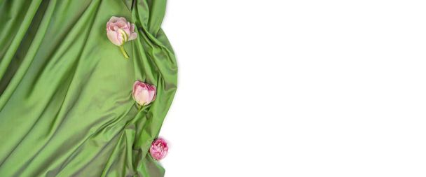 Банер веб-сайту. Ніжні рожеві тюльпани на зеленій м'якій тканині. Вид зверху. Зелений білий фон
.  - Фото, зображення
