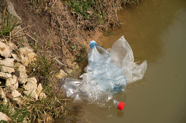 Забруднення пластику у воді. Пластикові відходи плавають у воді. Охорона довкілля. Пластикові пляшки та інші сміття на воді
. - Фото, зображення