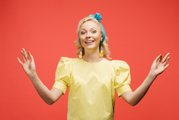 smiling blonde woman in blue headband gesturing on red  - Fotografie, Obrázek