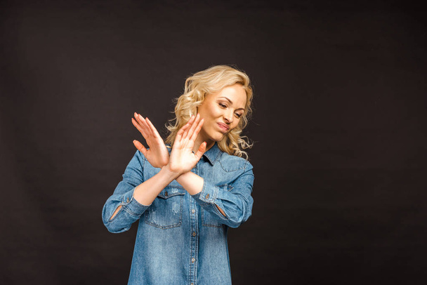 приваблива блондинка, яка не показує жестів, стоячи ізольовано на чорному
  - Фото, зображення