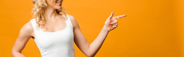 panoramic shot of blonde woman pointing with finger on orange  - 写真・画像