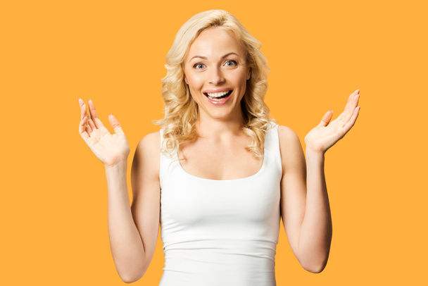 happy curly woman gesturing while smiling isolated on orange  - Photo, image