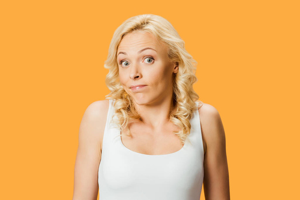 surprised woman in white t-shirt looking at camera isolated on orange - Foto, afbeelding