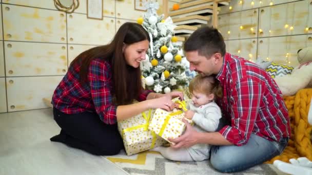 happy family with toddler daughter unpacking Christmas presents at home - Filmati, video