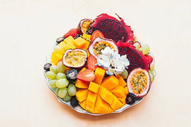 Червоні плоди драконів, виноград, манго і полуниця на тарілці на білому тлі. Гарне харчування, фрукти, багаті вітамінами. Свіжий салат. Тропічні фрукти
 - Фото, зображення