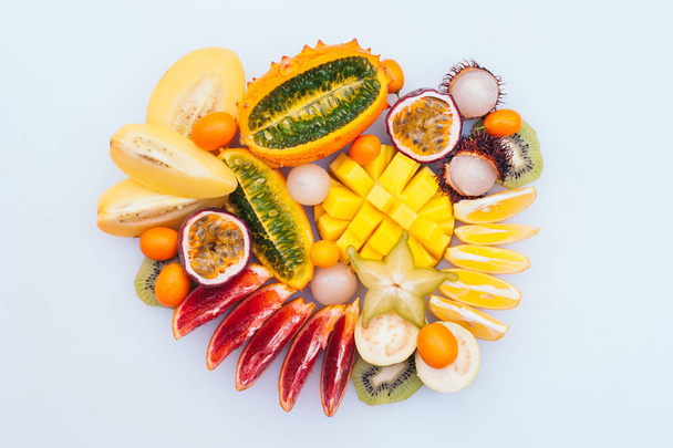 Φέτες από αστερίδη, μάνγκο, κιβάνο, ακτινίδιο, Rambutan που σχηματίζεται σε κύκλο απομονώνεται σε λευκό φόντο. Ποικιλία φρέσκων φρούτων. Πορτοκαλί αίμα. Βιταμίνες - Φωτογραφία, εικόνα