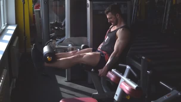 Handsome man at the gym doing exercises on leg - Video