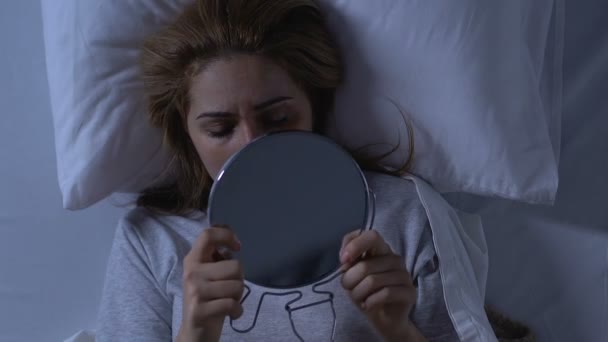 traurige Frau mit verletztem Gesicht, die im Bett liegt und in den Spiegel schaut, Gewaltopfer - Filmmaterial, Video
