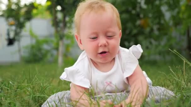 Küçük kız temiz havada. Montessori konsepti. Beyin gelişimi. Bebek gelişimi arka plan. Çocuklar ve doğa. Bebek ön, arka bahçesinde yeşil çim üzerinde güneşleniyor. - Video, Çekim