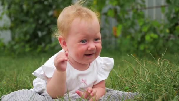 Miminka na kojení. Šťastný koncept dětství. Šťastný den matek. Modrooká dívka se usmívá venku. V časných podzimních dnech ležela na trávě malá hezká dívka. Dívka zkoumá svět kolem sebe - Záběry, video