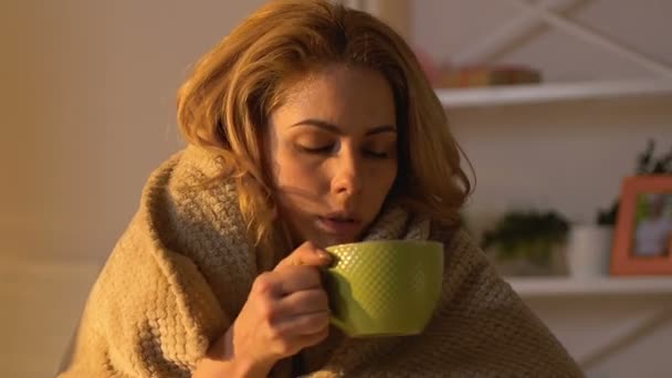 Sick woman covered in blanket drinking hot tea, non-traditional treatment - Séquence, vidéo