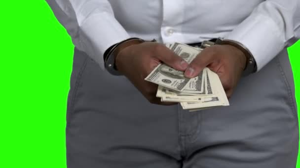 Человек в наручниках держит долларовые банкноты. - Кадры, видео