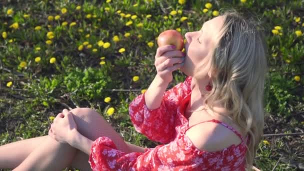 Nyár, fiatal nő eszik egy almát a természetben, lassú mozgás. - Felvétel, videó