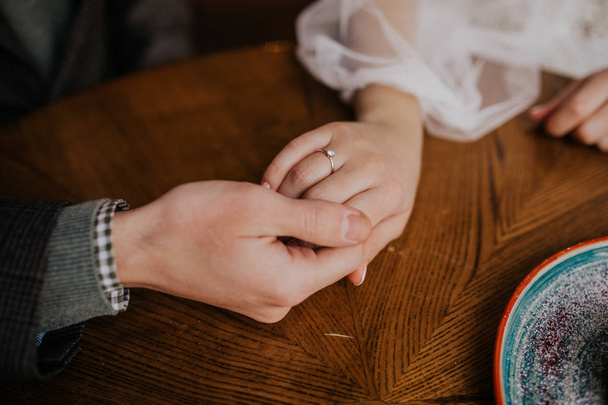 cropped shot of bride and groom holding hands at table - Fotó, kép