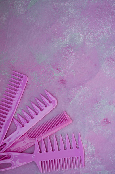 美容師のためのピンクの明るい櫛。美容サルーン。ヘアスタイルのためのツール。ピンクの背景。理髪 店。異なるヘアブラシのセット。テキスト用のスペース. - 写真・画像