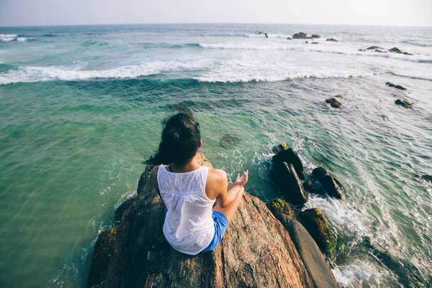 Young yoga woman meditating on seaside on rock cliff   - Φωτογραφία, εικόνα