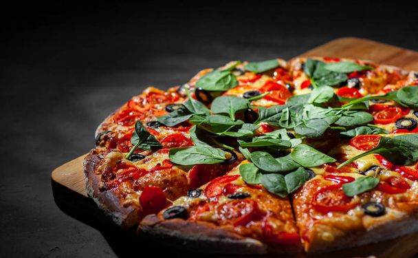 Pizza with Mozzarella cheese, Tomatoes, pepper, olive, Spices and Fresh spinach. Italian pizza. Pizza Margherita or Margarita on Dark grey black slate background - Foto, immagini