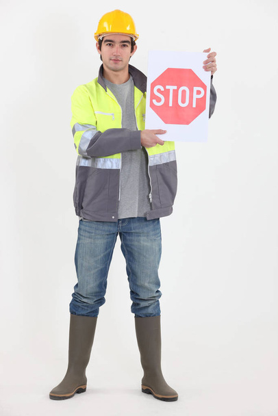 A road worker holding a stop sign. - Foto, afbeelding