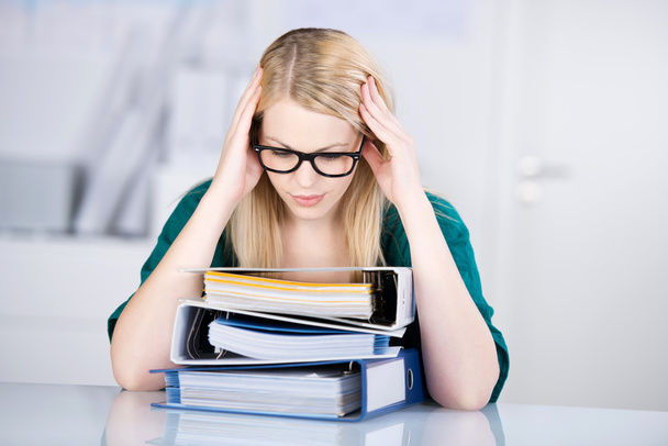 Overworked Businesswoman Looking At Stack Of Binders At Desk - Foto, Bild