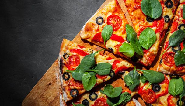 Pizza with Mozzarella cheese, Tomatoes, pepper, olive, Spices and Fresh spinach. Italian pizza. Pizza Margherita or Margarita on Dark grey black slate background - Foto, Imagem