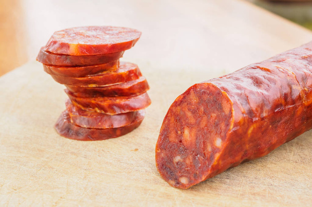 Иберийский чоризо, испанский чоризо или испанская колбаса, разрезанная на ломтики на деревянной доске. Типичное испанское блюдо
 - Фото, изображение
