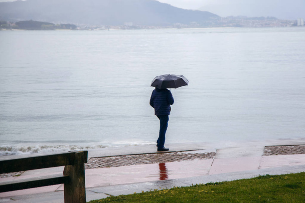a man with an umbrella is walking along the embankment, it is raining, the Atlantic Ocean, bad weather - Photo, Image