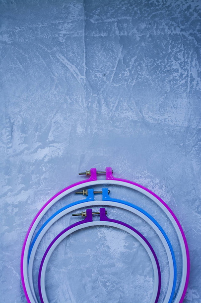 Cerchio di plastica su uno sfondo leggero sotto il cemento. Tre cerchi rosa, blu, viola. Vista dall'alto. Spazio sotto il testo
. - Foto, immagini