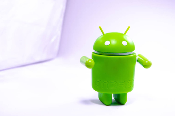 2019 Απριλίου. Λος Άντζελες, ΗΠΑ. Πράσινο πλαστικό Android σχήμα σε λευκό φόντο και με ένα smartphone. Σχήμα, λογότυπο Android, Google - Φωτογραφία, εικόνα