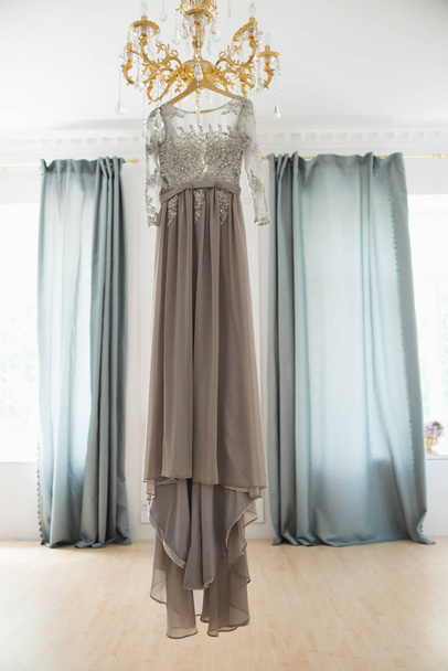 γκρι νυφικό φόρεμα σε κρεμάστρα που κρέμεται από πολυέλαιο - Φωτογραφία, εικόνα