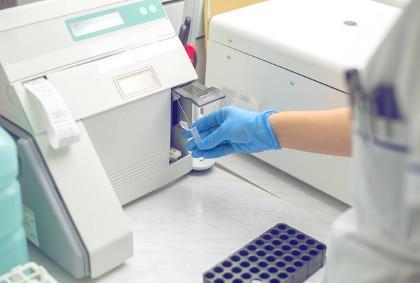 Γυναίκα που εργάζεται σε ένα εργαστήριο σε ένα σύγχρονο μηχάνημα για την εξέταση αίματος - Φωτογραφία, εικόνα