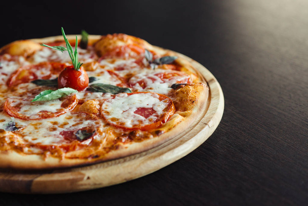 Pizza italiana en el tablero en la mesa oscura
 - Foto, Imagen