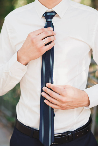 un tipo con una camisa blanca endereza su corbata azul
 - Foto, imagen