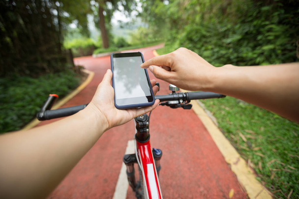 person using smartphone app for navigation while having bike ride on the forest trail - Foto, Bild