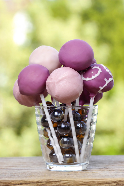 Violet and lilac cake pops on wooden rustic table in summer gard - Фото, зображення