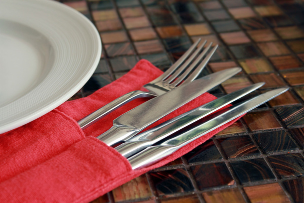 Tenedor, cuchillos y un plato yacen sobre una mesa en el restaurante
 - Foto, Imagen