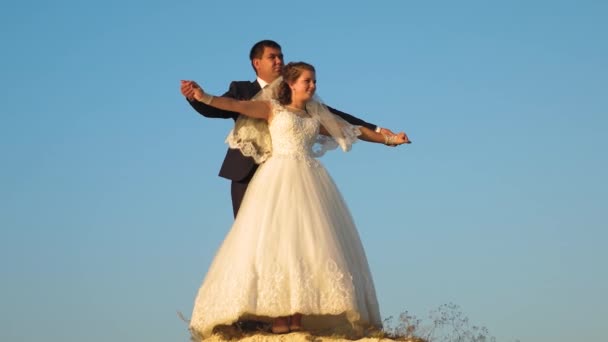 bride and groom dancing against blue sky. teamwork. happy family concept. Romantic man and woman hover against the blue sky and smile. Honeymoon. Romance. The relationship between a man and a woman. - Footage, Video