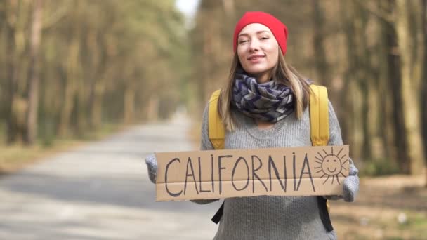 Κορίτσι οτοστόπ μείνει σε άδειο δρόμο σε ξύλο με αφίσα Καλιφόρνια  - Πλάνα, βίντεο