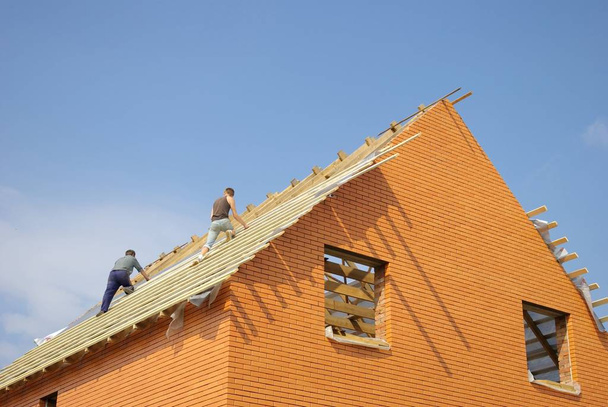 Construction workers placing the first section of roof on a new home under construction. - Foto, Imagem