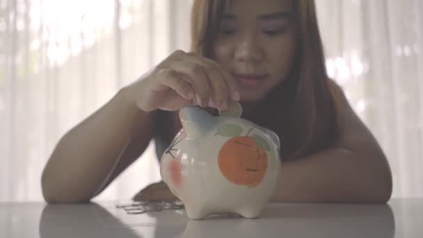 Woman inserts a coin into a piggy bank - Footage, Video