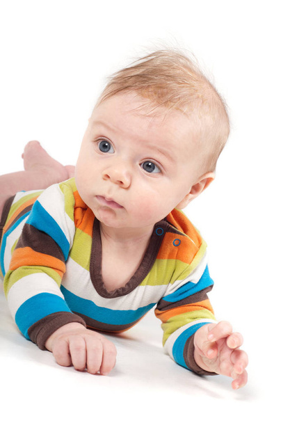 Shot of little baby  in multicolored striped clothes lying on white background - Фото, зображення
