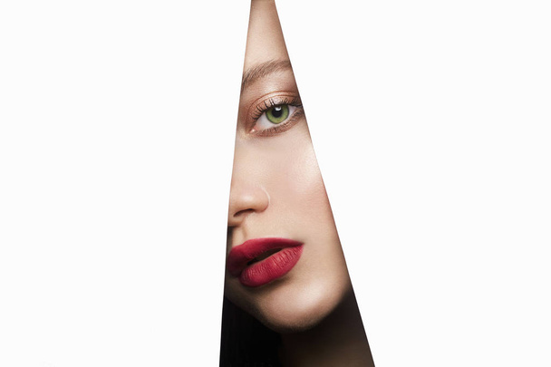 женское лицо с макияжем в бумажном отверстии. make-up
 - Фото, изображение