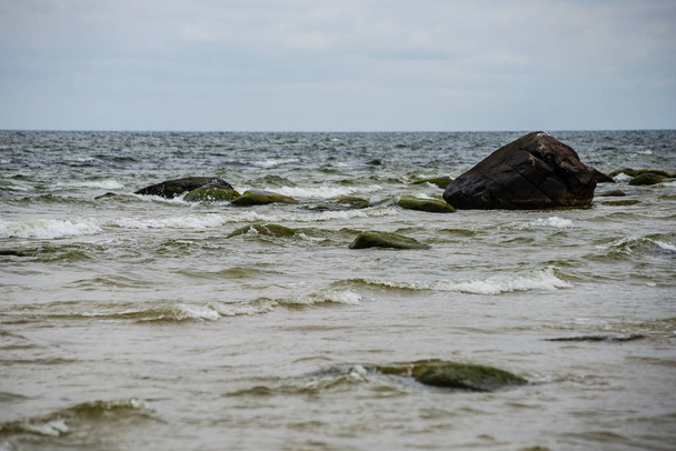 praia de mar tempestuoso com grandes rochas na areia molhada. Mar Báltico
 - Foto, Imagem